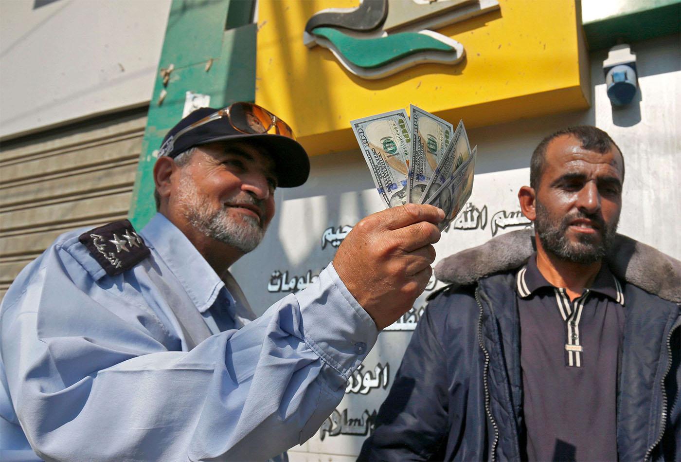 A Palestinian man shows his money after receiving his salary in Rafah in the southern Gaza Strip