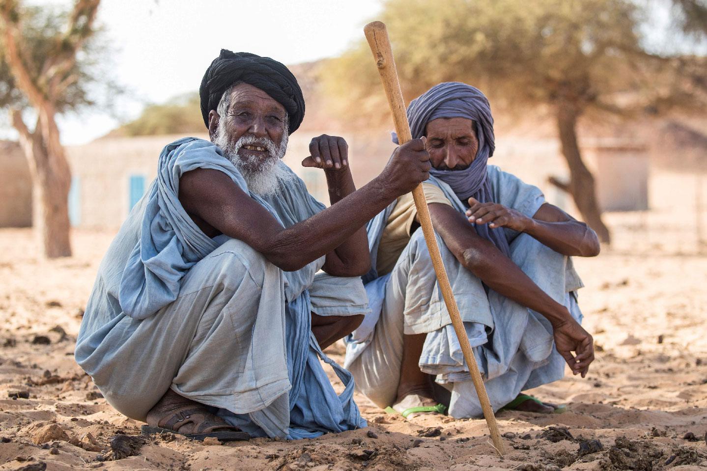 Men sit on the ground in Ouad Initi, eastern Mauritania, on November 21, 2018.