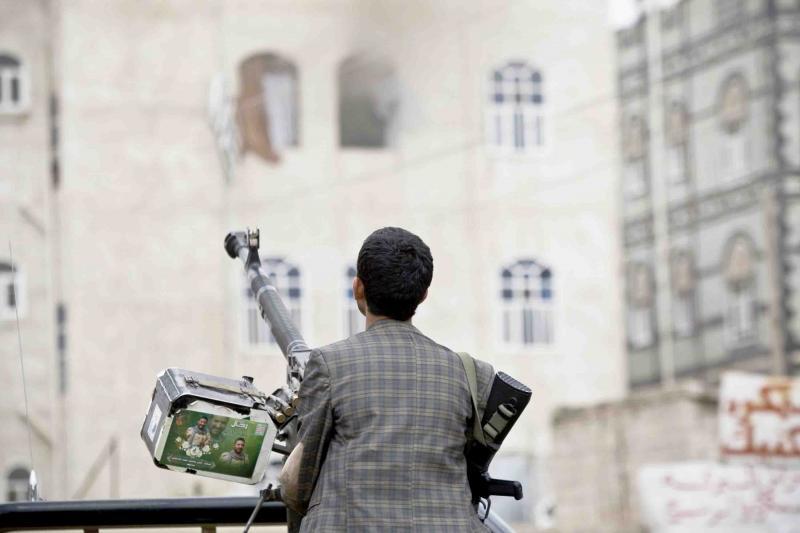 A Houthi fighter holds a weapon as he looks at smoke rising from a building in Sana’a