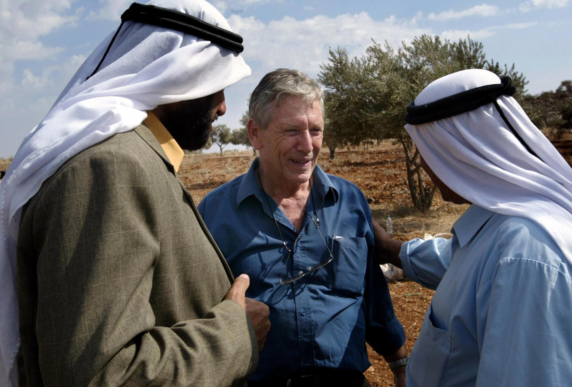 In this file photo taken on October 30, 2002 Israeli writer Amos Oz (C) talks with Palestinian men after picking olives in the West Bank village of Aqraba, south of Nablus.