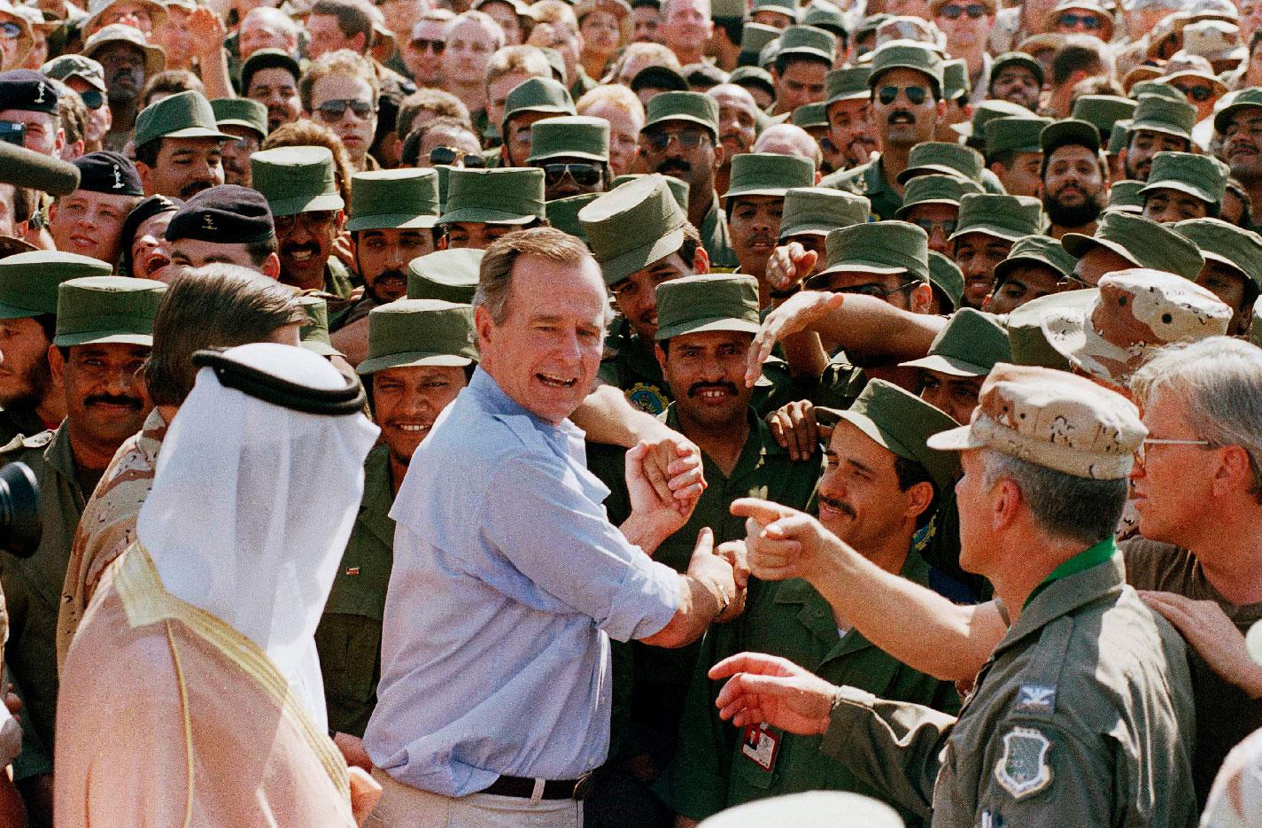 A file photo shows former US President George H.W. Bush being greeted by Saudi troops and others as he arrives in Dhahran, Saudi Arabia, in 1990.