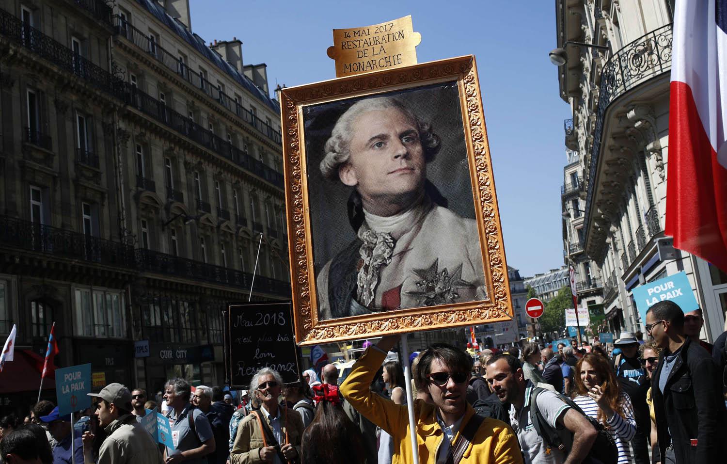 متظاهرون يرفعون صورة مركبة للرئيس إيمانويل ماكرون على لوحة لملك فرنسا لويس السادس عشر