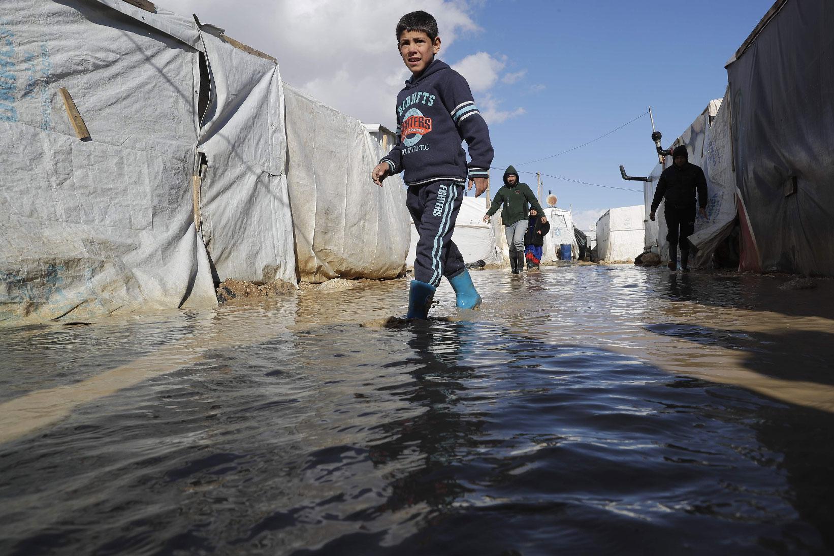 A child wades through rain and snow waters at an informal tent settlement housing Syrian refugees following winter storms in the area of Delhamiyeh, in the central Bekaa Valley on January 17, 2019.