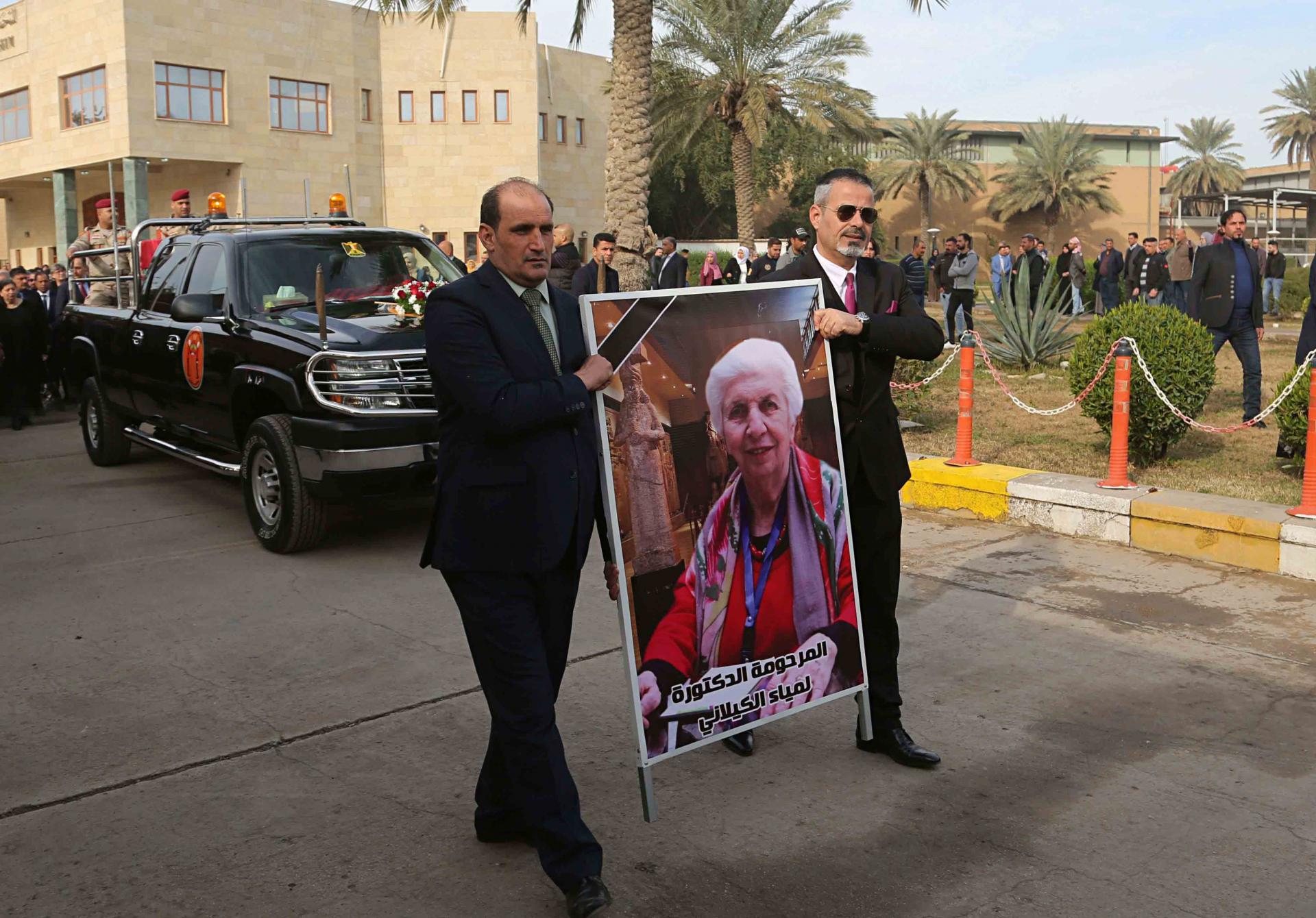 Mourners transport the flag-draped coffin of Iraqi archaeologist, Lamia al-Gailani, seen in the poster, for burial during her funeral procession in the National Museum in Baghdad, Iraq, Monday, Jan. 21, 2019