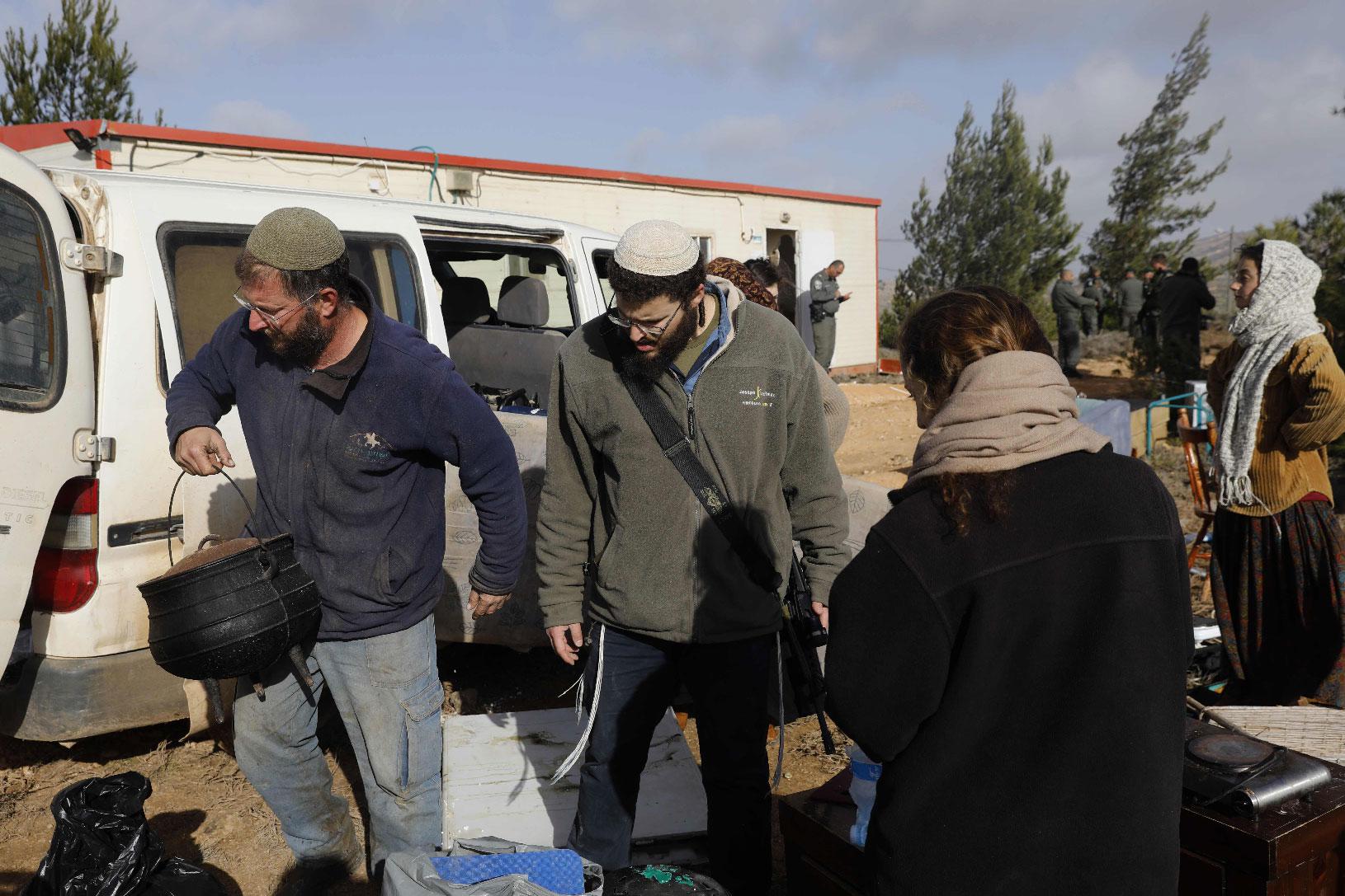 Israeli settlers move their belongings outside a caravan they had brought to the former outpost of Amona near the Jewish settlement of Ofra, following clashes with security forces as dozens of settlers were evicted early on January 3, 2019.