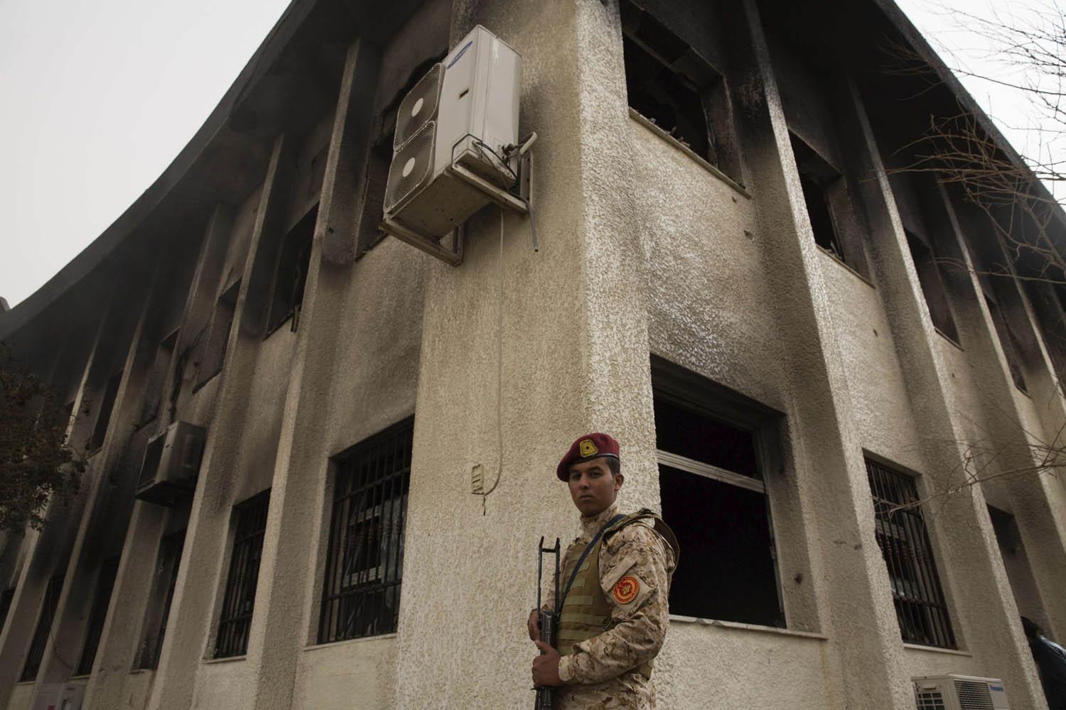 جندي ليبي أمام مبنى محترق في طرابلس