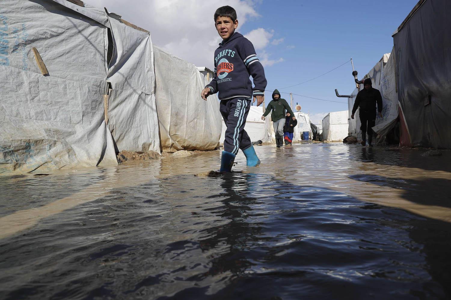 طفل يخوض في مياه الأمطار في مخيم للاجئين السوريين في البقاع الأوسط في لبنان