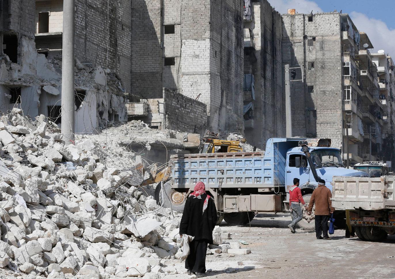 A tractor and trucks remove the rubble from buildings that were heavily damaged or destroyed during battles between rebel fighters and regime forces, in the former opposition held district of Salaheddin in the northern Syrian city of Aleppo on February 11, 2019.
