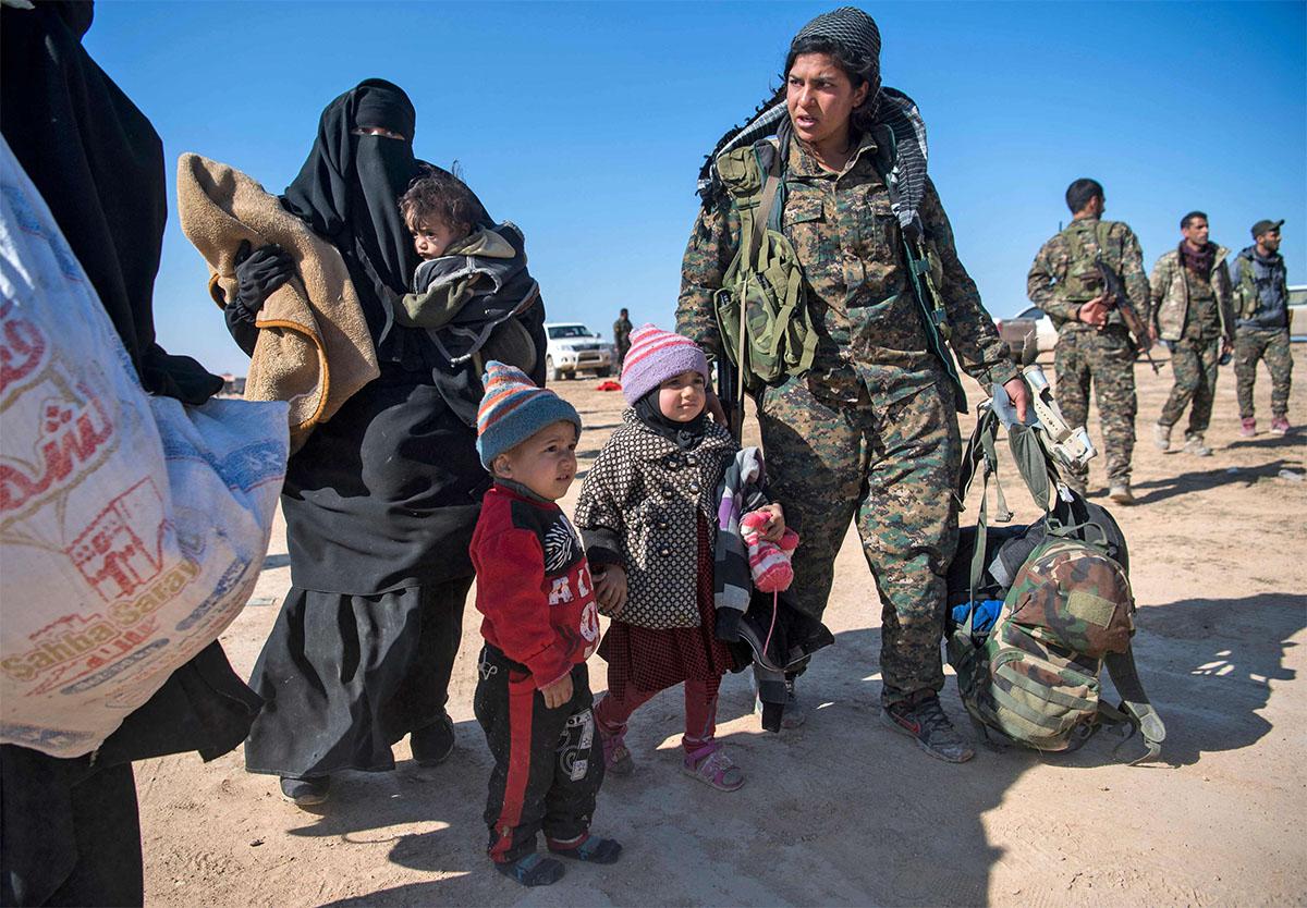 SDF fighter helps civilians fleeing from the Baghouz area