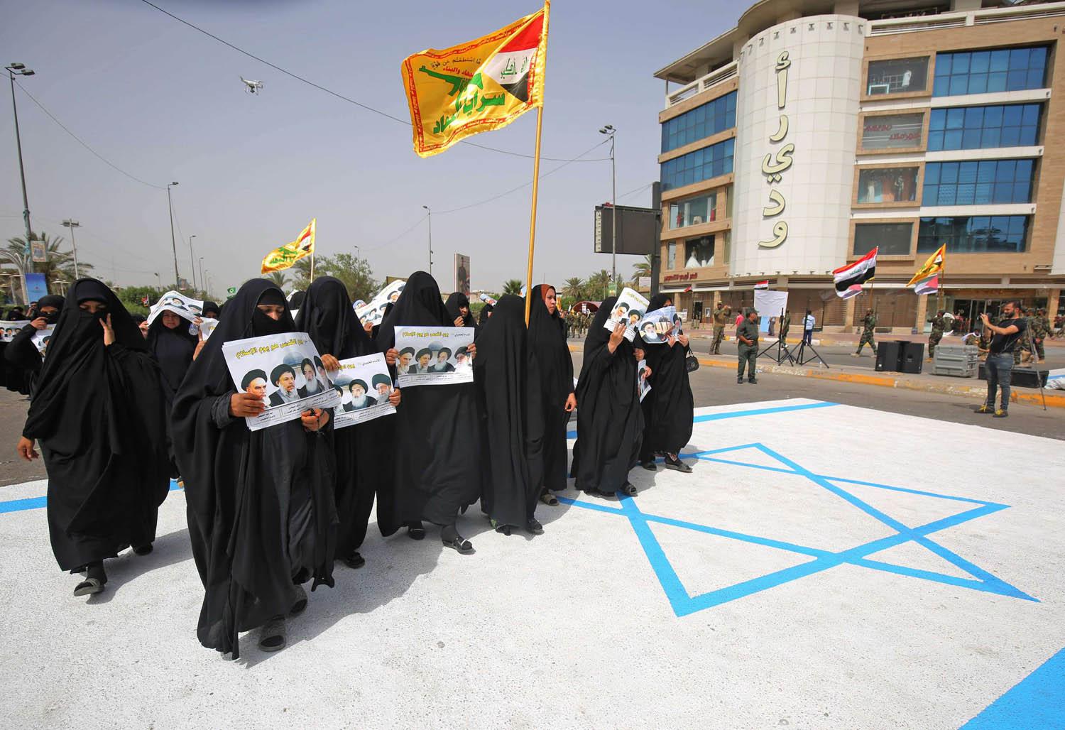 عراقيات يحملن صورا للخميني وخامنئي في تظاهرة ضد إسرائيل في بغداد