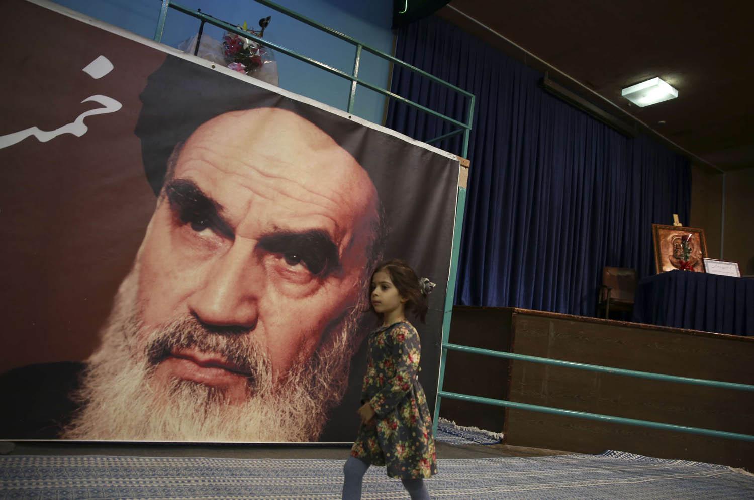 طفلة تمر بجانب صورة الخميني في طهران