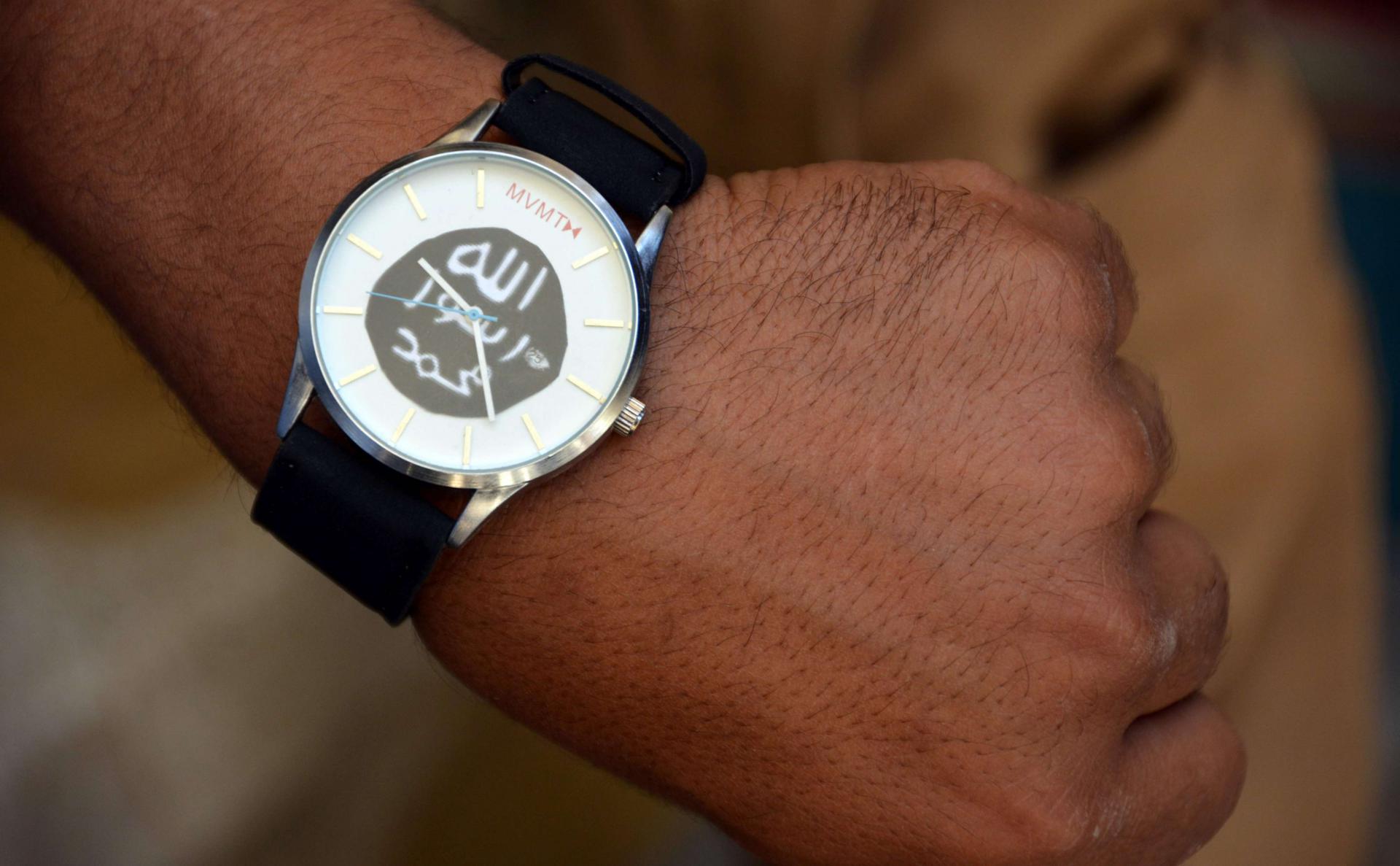 A member of the Iraqi special forces puts on a watch belonging to a former Islamic State (IS) group fighter, bearing the group's logo, found by security forces in the Old City of Mosul, in the city's western industrial district on June 29, 2017.