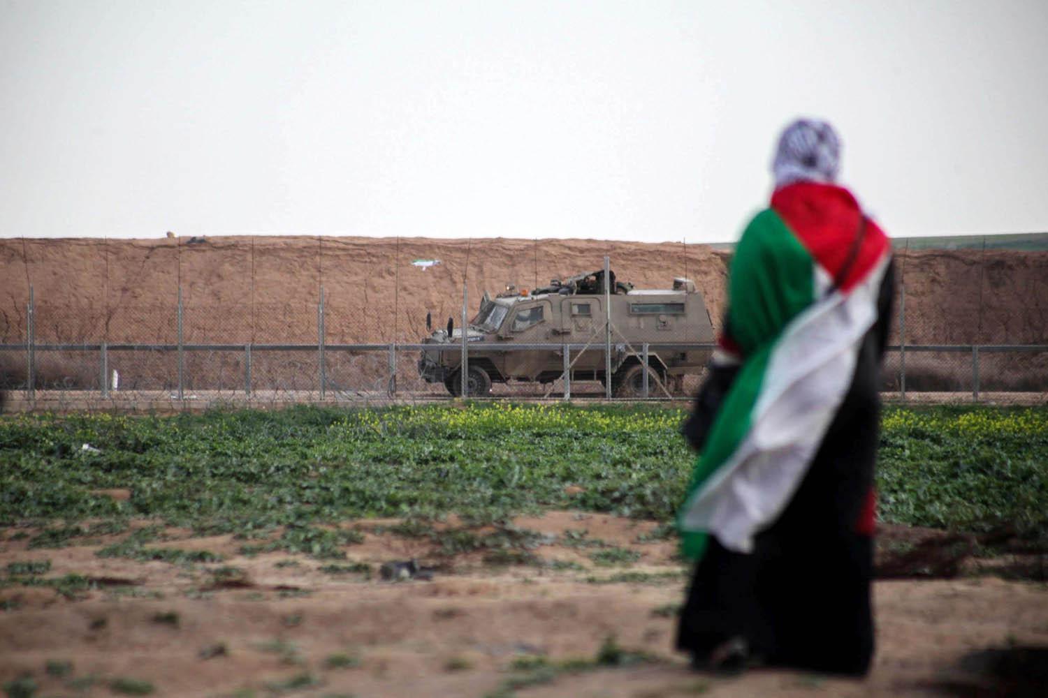 امرأة فلسطينية أمام عربة مدرعة إسرائيلية على الحدود بين إسرائيل وغزة