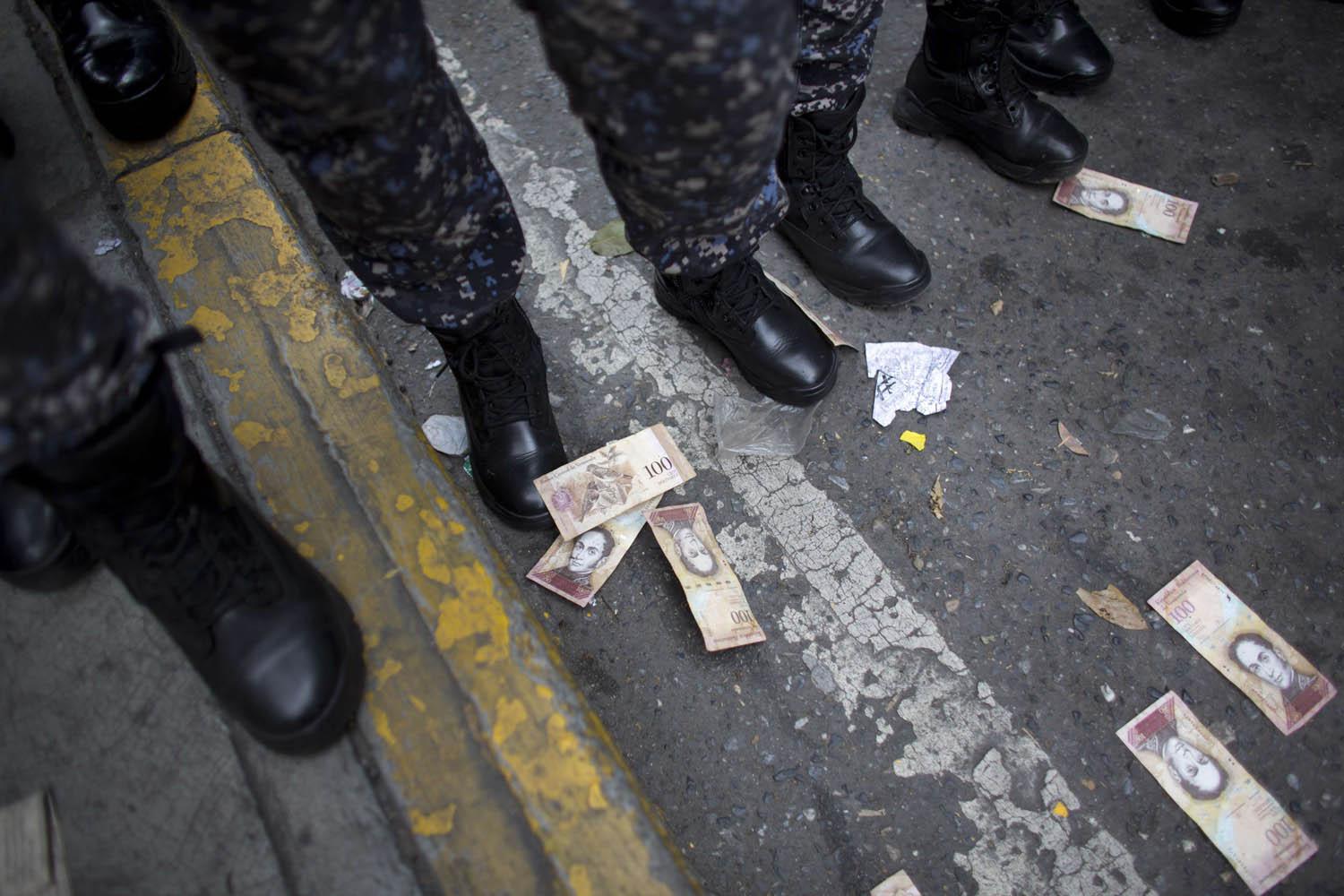 متظاهرون يلقون أوراق نقدية تحت اقدام جنود خرجوا لمنع التظاهرات في كراكاس