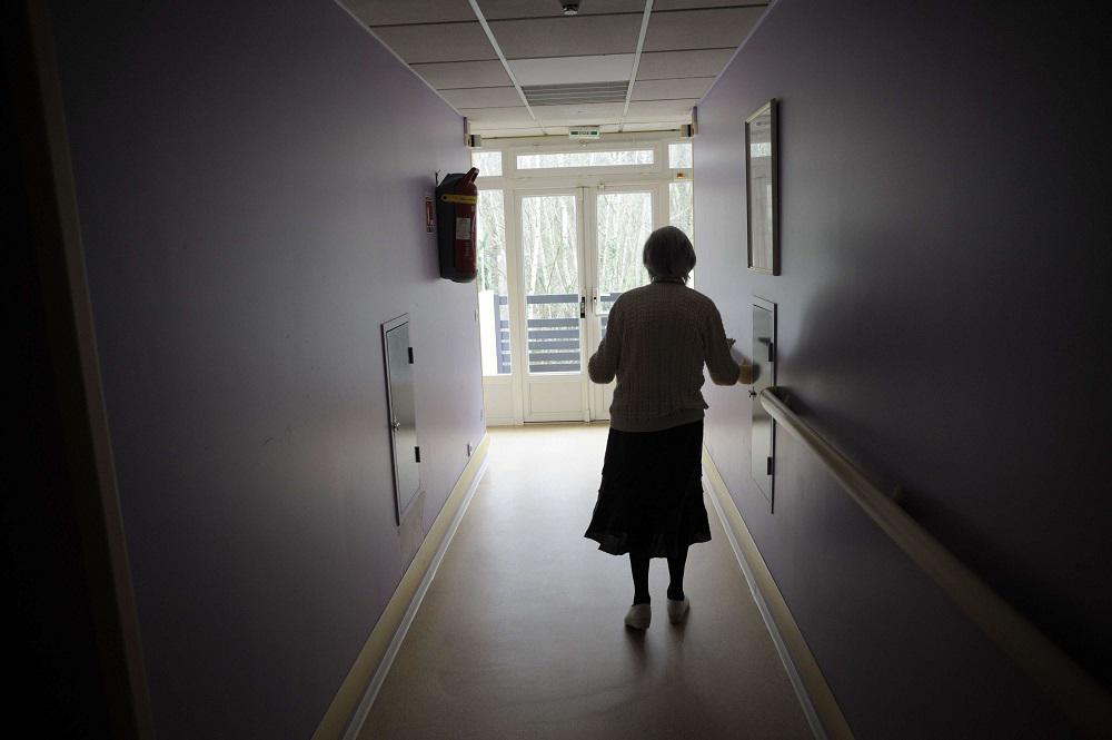 امرأة فرنسية مسنة مصابة بالزهايمر تمشي في ممر أحد المستشفيات