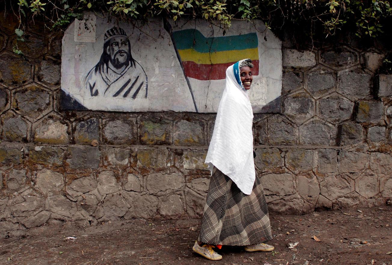 A traditionally-dressed Ethiopian woman walks past a mural depicting Ethiopia's Emperor Tewodros II in Addis Ababa, Ethiopia, June 1, 2007.