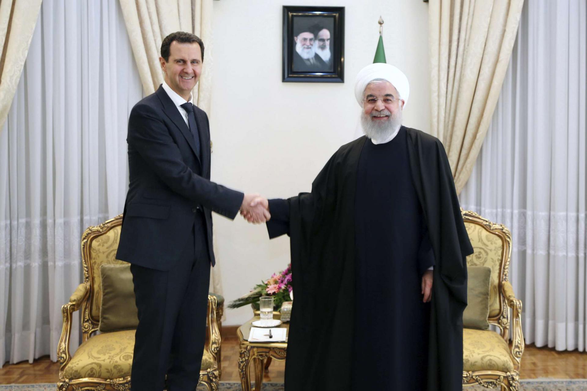 President Hassan Rouhani, (R) shakes hands with Syrian President Bashar Assad before their meeting at his office in Tehran, Iran, February. 25