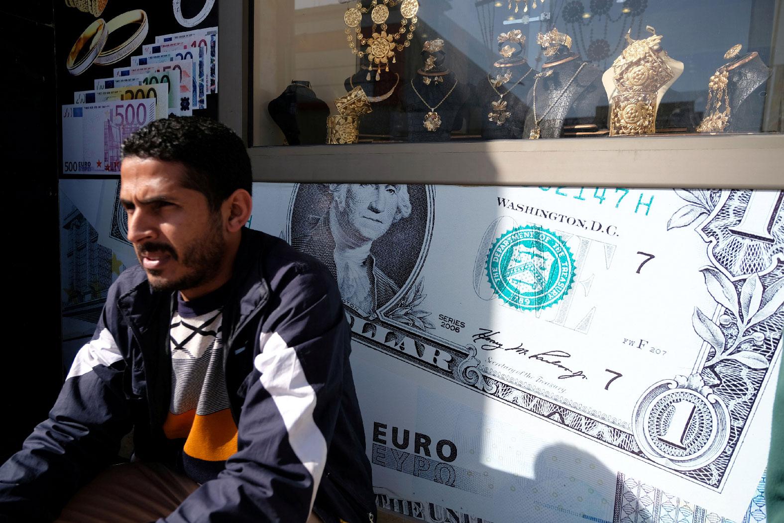 A man sits next to a gold shop and a currency exchange in Benghazi, Libya February 4, 2019.