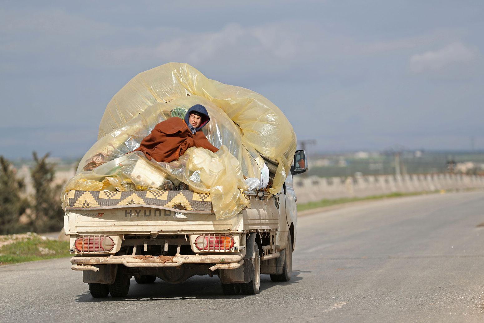 A Syrian man sits at the back of a truck as he leaves from Saraqib on February 27, 2019.
