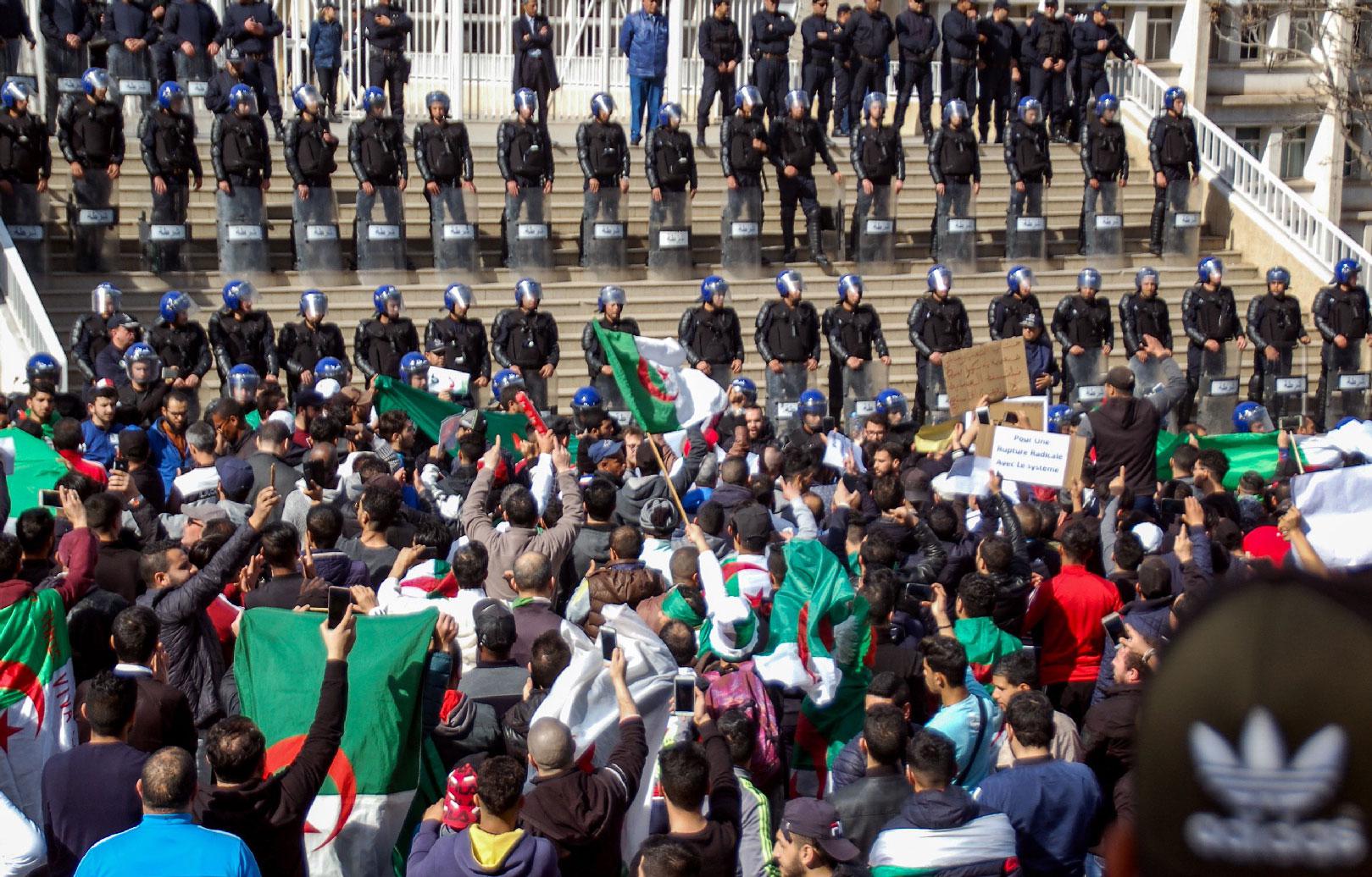 Algerians shout slogans and raise signs and national flags as they protest outside the city hall in the northern coastal city of Oran, about 410 kilometres west of the capital Algiers, on March 1, 2019, during a rally against ailing President Abdelaziz Bouteflika's bid for a fifth term in power.