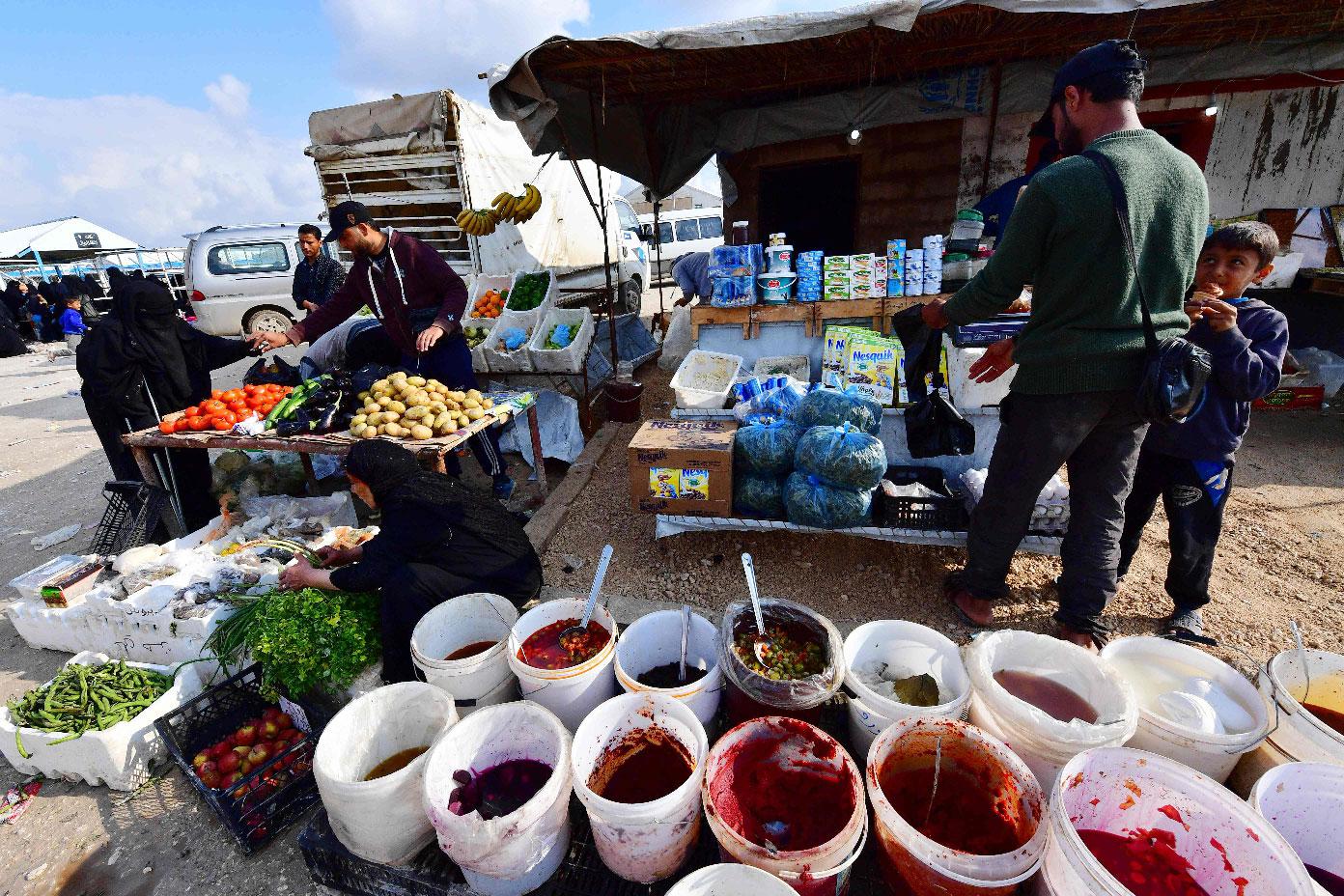 Street vendors sell pickles and vegetables on March 28, 2019 in the souk or market of Al-Hol camp for displaced people in northeastern Syria, which currently brims with more than 70,000 people, even though it was only designed to accommodate a seventh of that number.