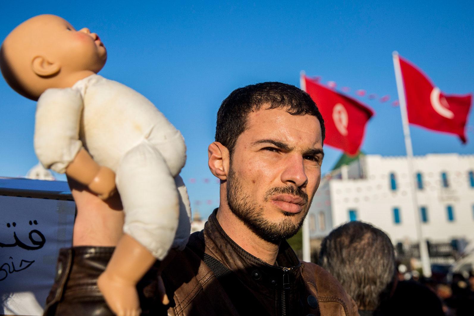 A Tunisian protester holds a baby doll in Tunis to denounce the deaths of babies in Tunisian hospital, Tuesday, March 12, 2019.
