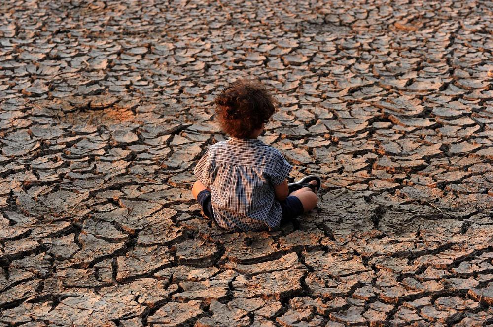 طفل يجلس على تربة جافة في منطقة تأثرت بالجفاف في تيغوسيغالبا عاصمة هندوراس