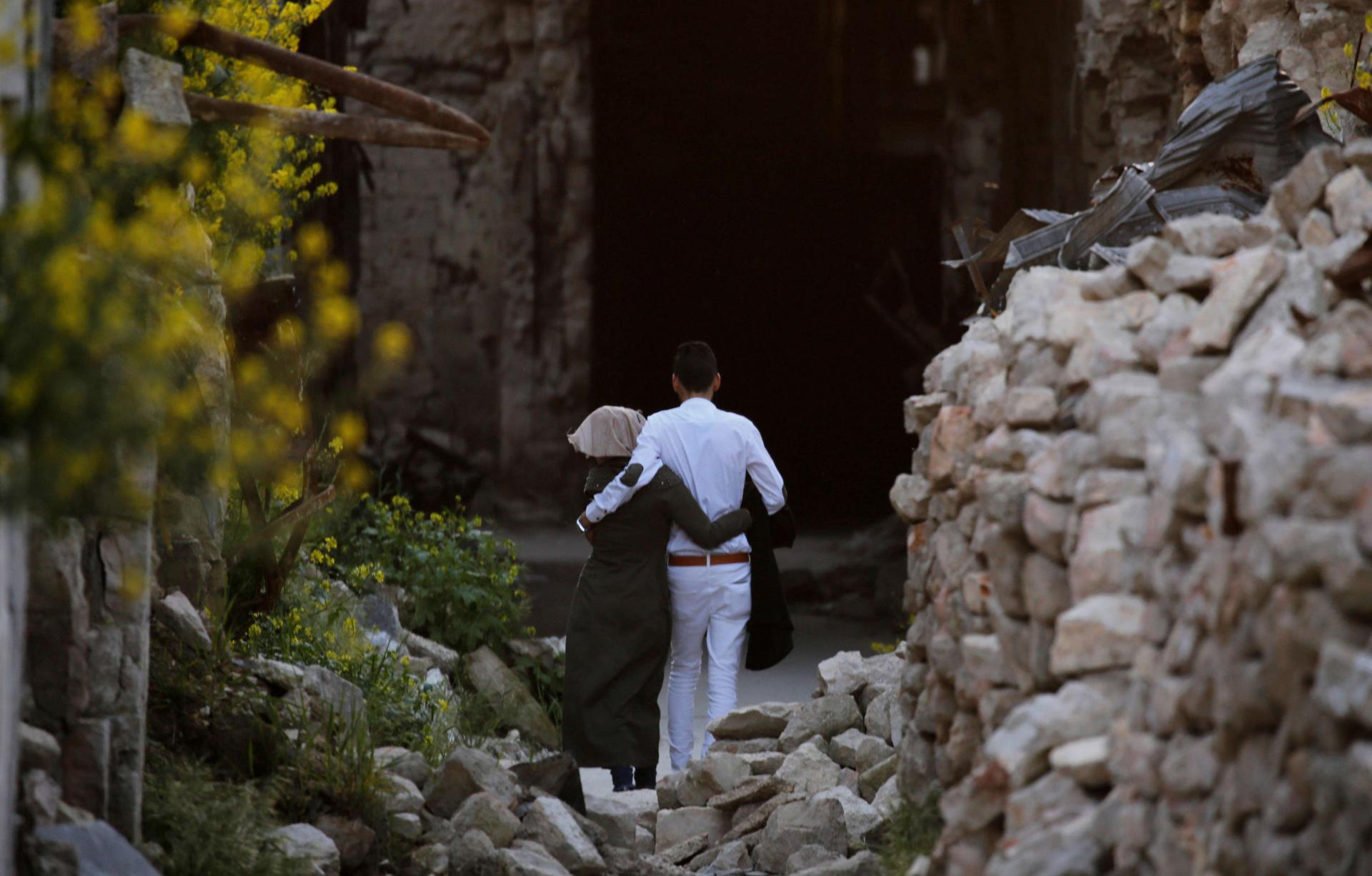 زوجان يمشيان على أنقاض المتاجر المتضررة في مدينة حلب القديمة 