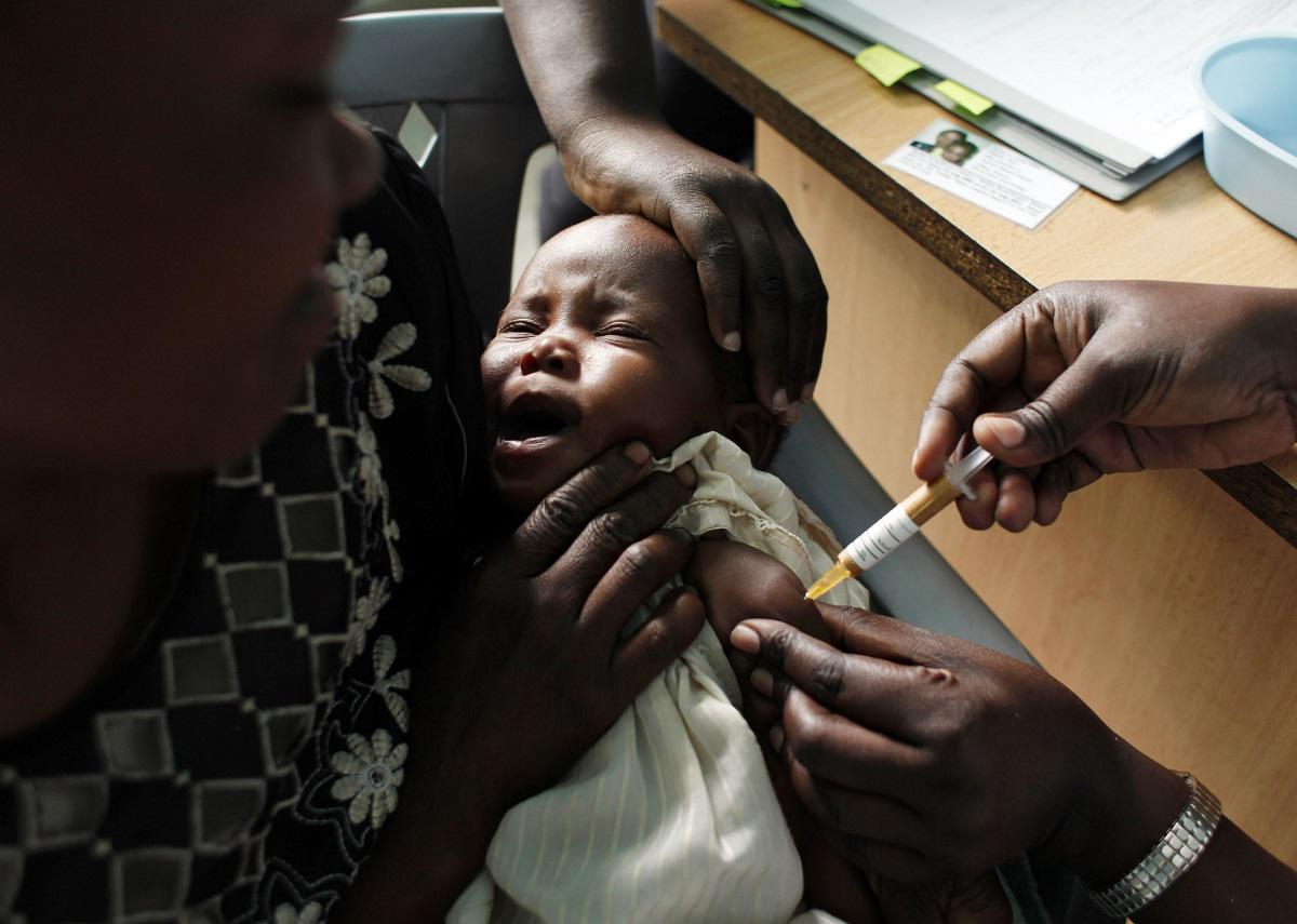 أم تمسك بطفلها الذي يتلقى لقاحا ضد الملاريا في كينيا