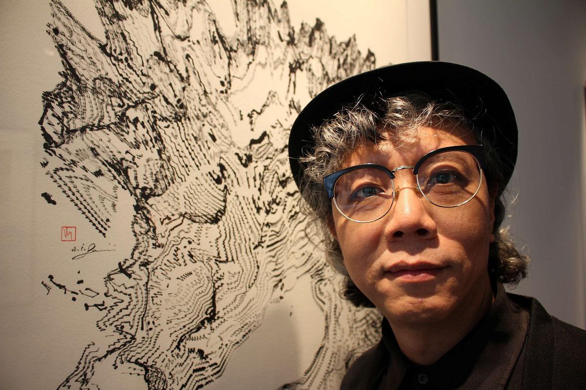 الفنان الصيني فيكتور وونغ يقف بجانب لوحة رسمها الروبوت في معرض بلندن