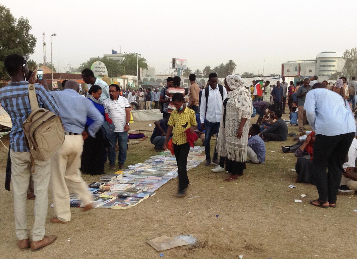 سودانيون يتجمعون حول كتب مفروشة على الارض