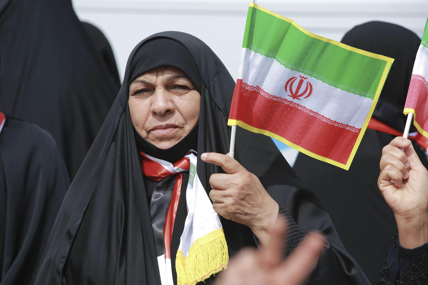 عراقية تحمل علما إيرانيا في تجمع للحشد الشعبي في بغداد