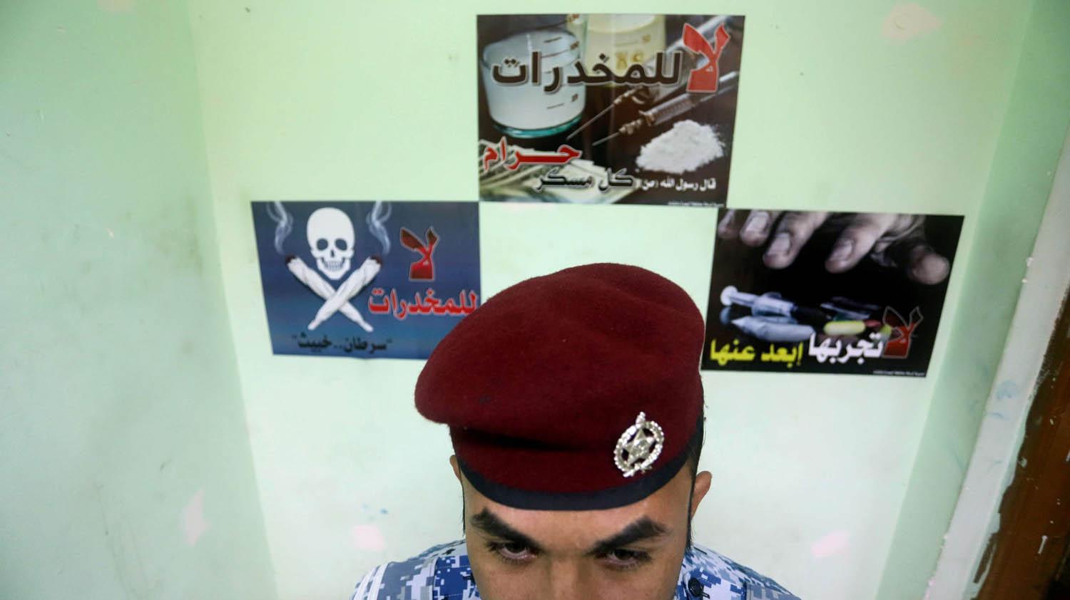 شرطي عراقي أمام ملصقات لمحاربة انتشار المخدرات في البصرة