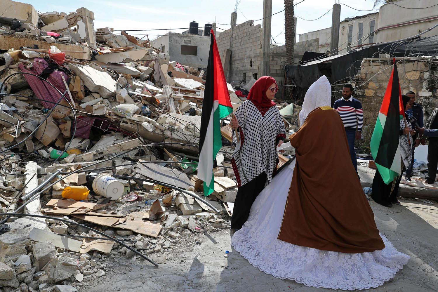 عروس فلسطينية تمر أمام بيتها الذي دمرته غارة إسرائيلية على غزة