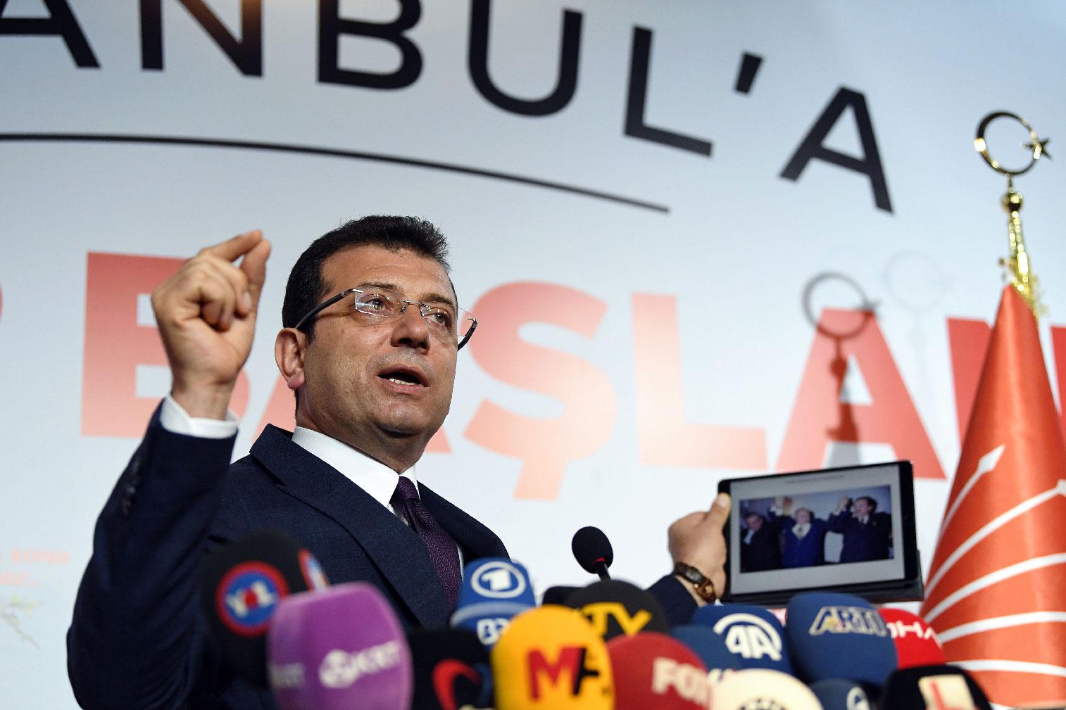 Turkey's main opposition party CHP candidate Ekrem Imamoglu, who claimed victory as Istanbul mayor, shows a picture of the 1994 local election featuring Istanbul Metropolitan municipality Refah Party (RP) candidate Recep Tayyip Erdogan (R), conservative Refah Party (RP) leader Necmettin Erbakan (C) and his opponent Social Democratic Populist Party (SHP) Nurettin Sozen, on his tablet during a press conference at the CHP's Election Coordination Centre in Istanbul on April 3, 2019.