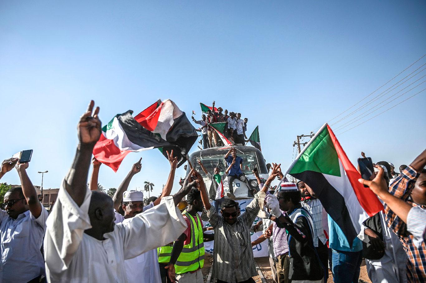 Sudanese protesters from the city of Atbara, sitting atop a train, arrive at the Bahari station in Khartoum