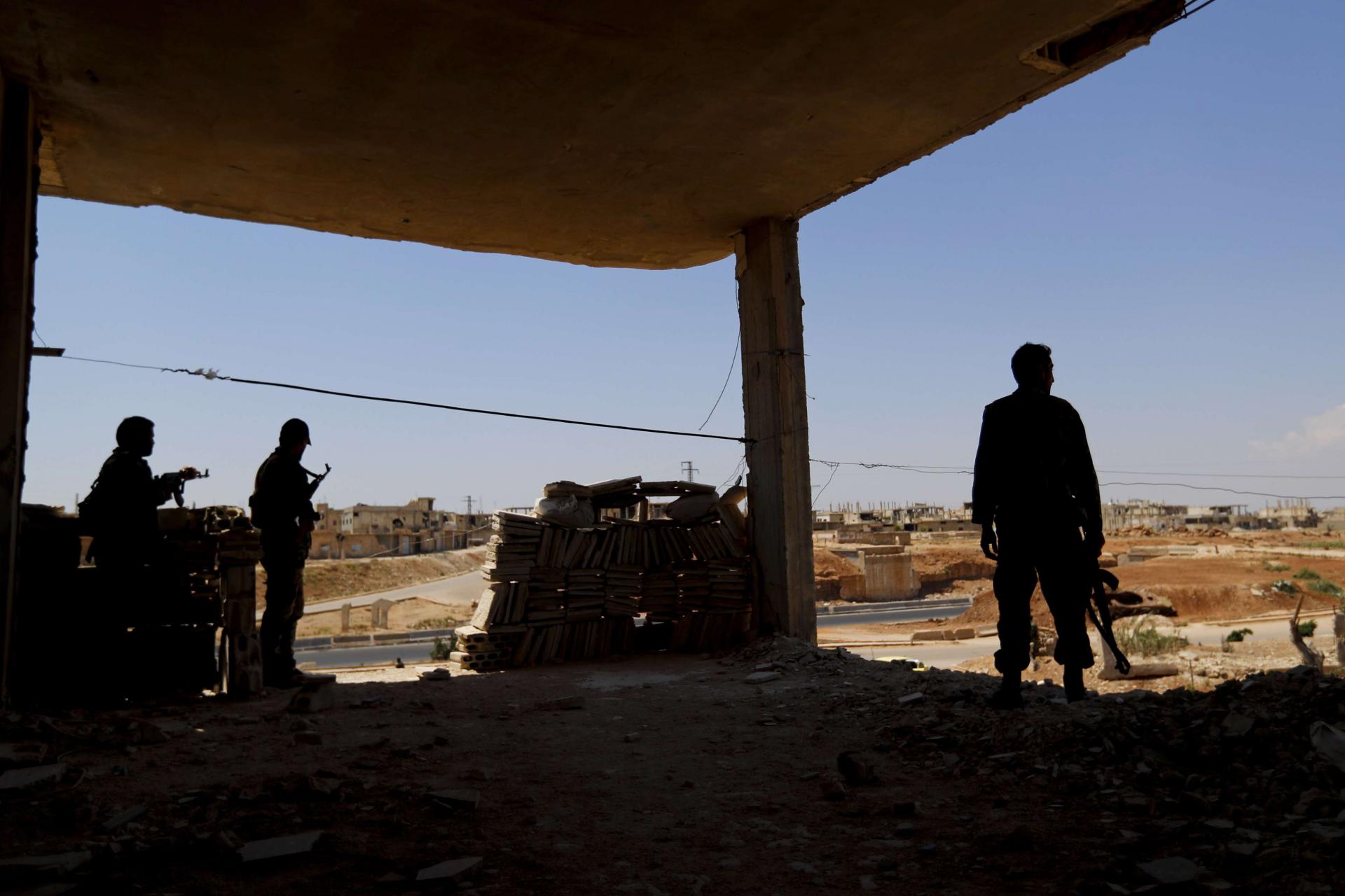 Syrian soldiers stand guard at their post overlooking the Damascus-Aleppo highway
