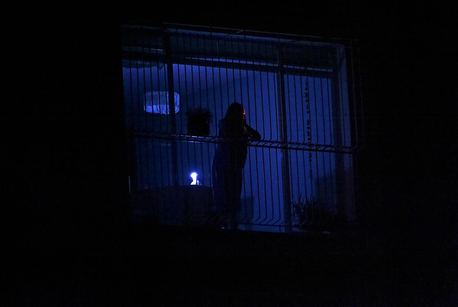 إمرأة فنزويلية تطل من شباك في كراكاس خلال انقطاع تام للتيار الكهربائي