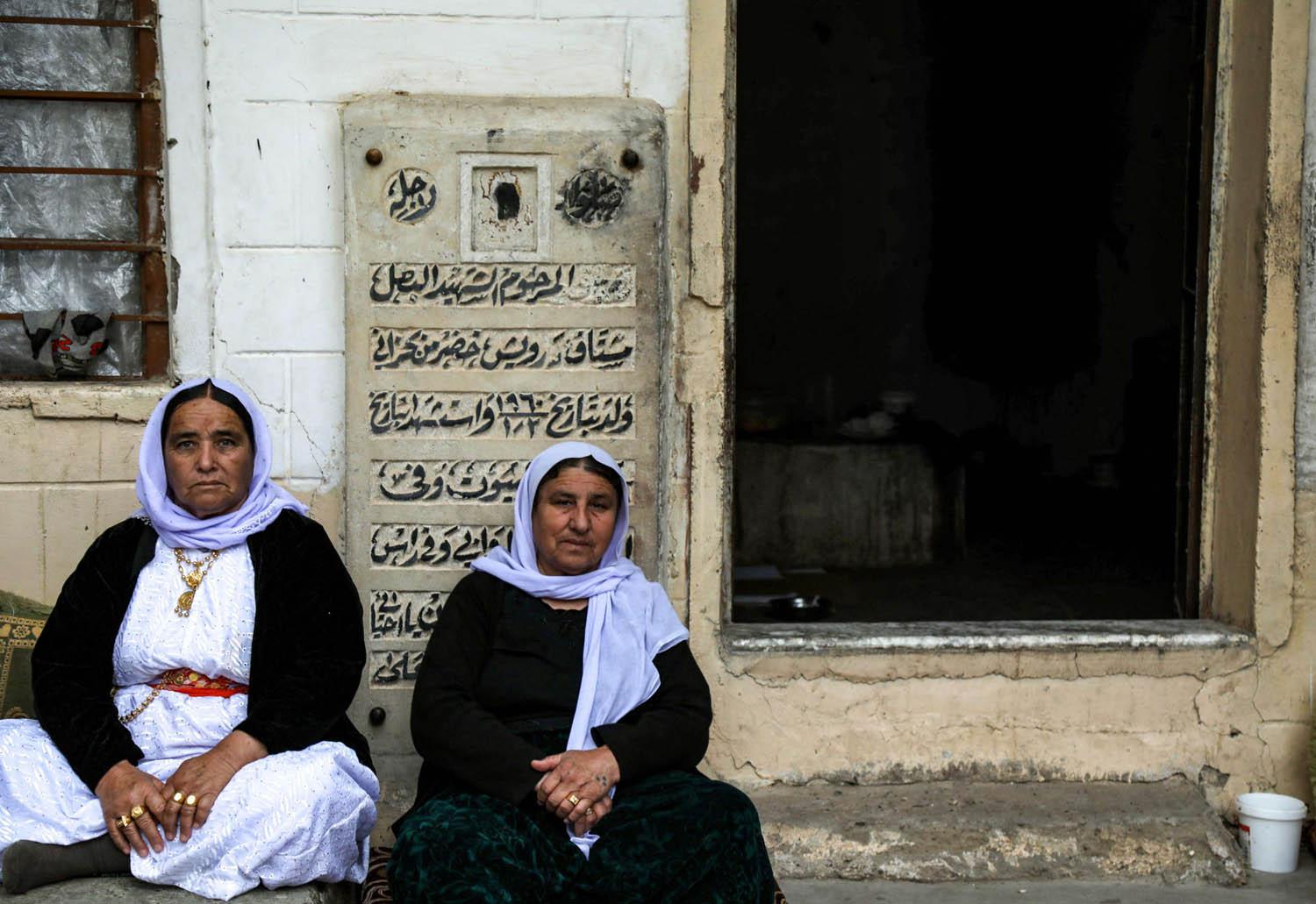 يزيديات يجلسن عند بوابة مقبرة في لاليش قرب دهوك في شمال العراق
