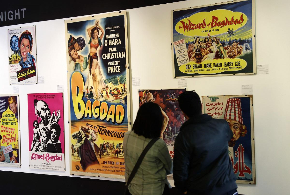 شاب وفتاة يقفان أمام ملصقات لافلام قديمة في معرض "لص بغداد" في بيروت