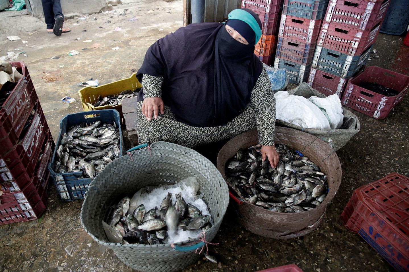 A woman sells fish caught by her husband at the market in Egypt's Nile Delta village of El Shakhluba