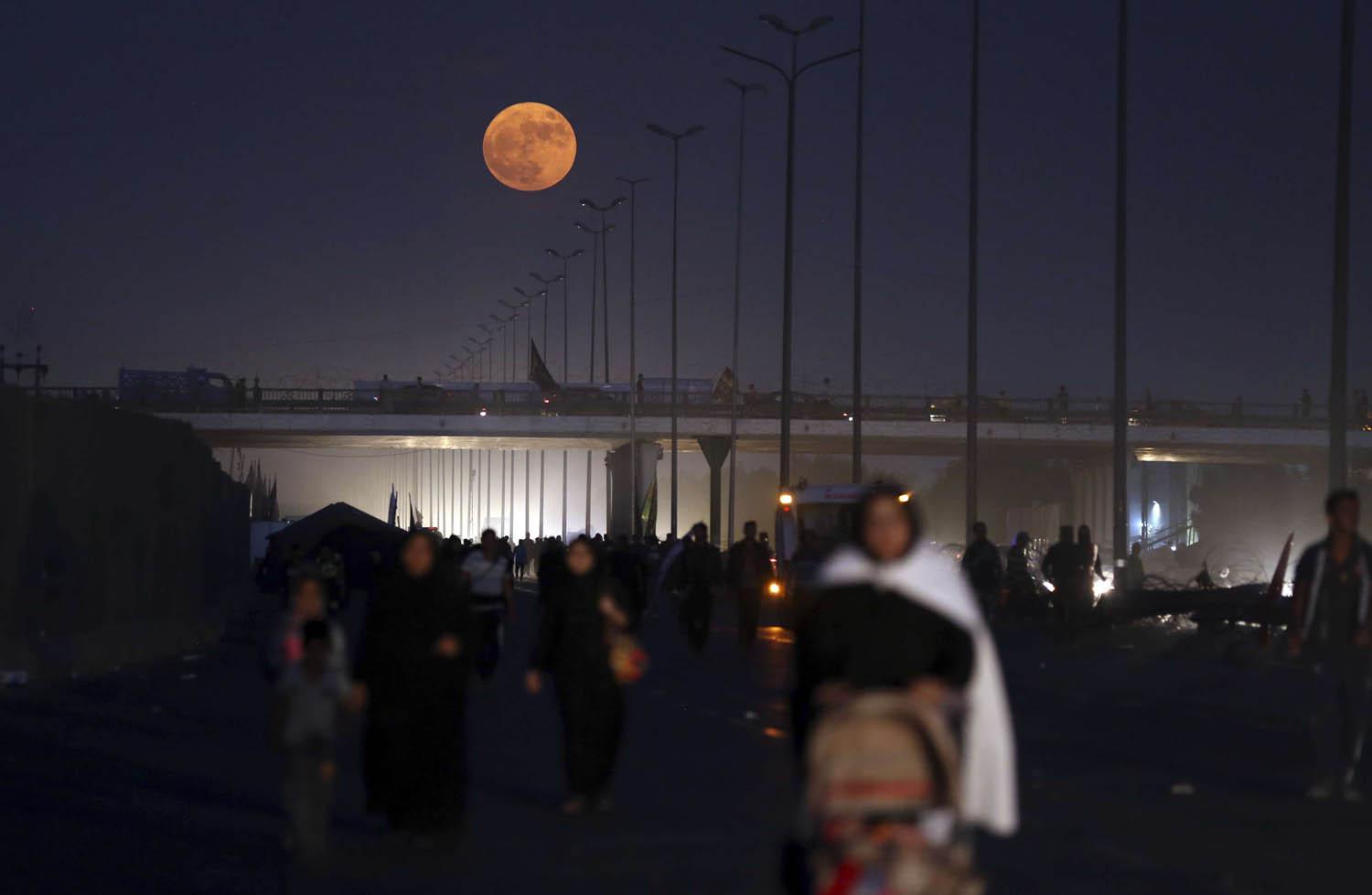 عراقيون يمشون في كربلاء في موسم زيارة الأضرحة