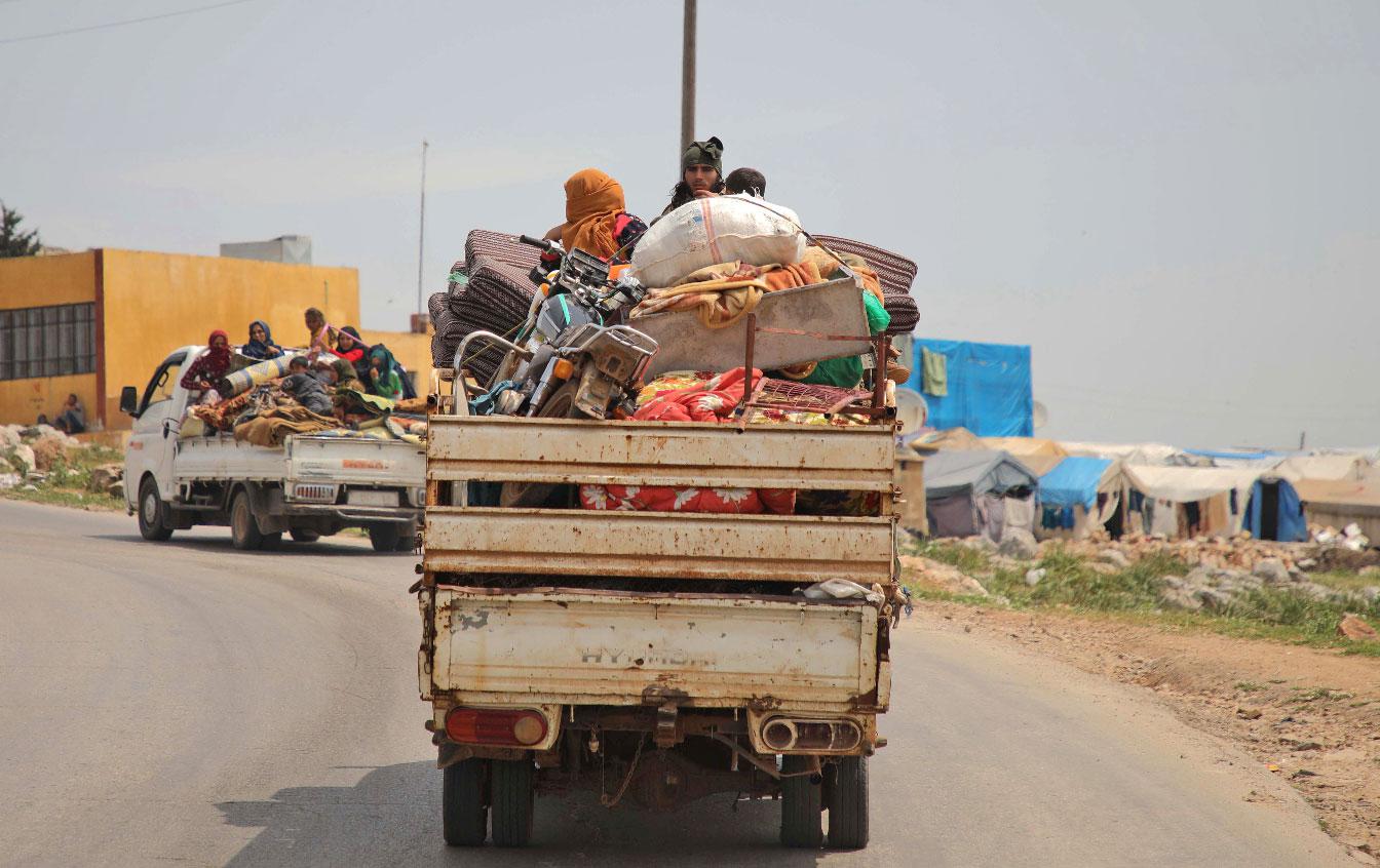 Syrian families, riding in the back of trucks loaded with their belongings, flee from reported regime shelling on Hama and Idlib provinces
