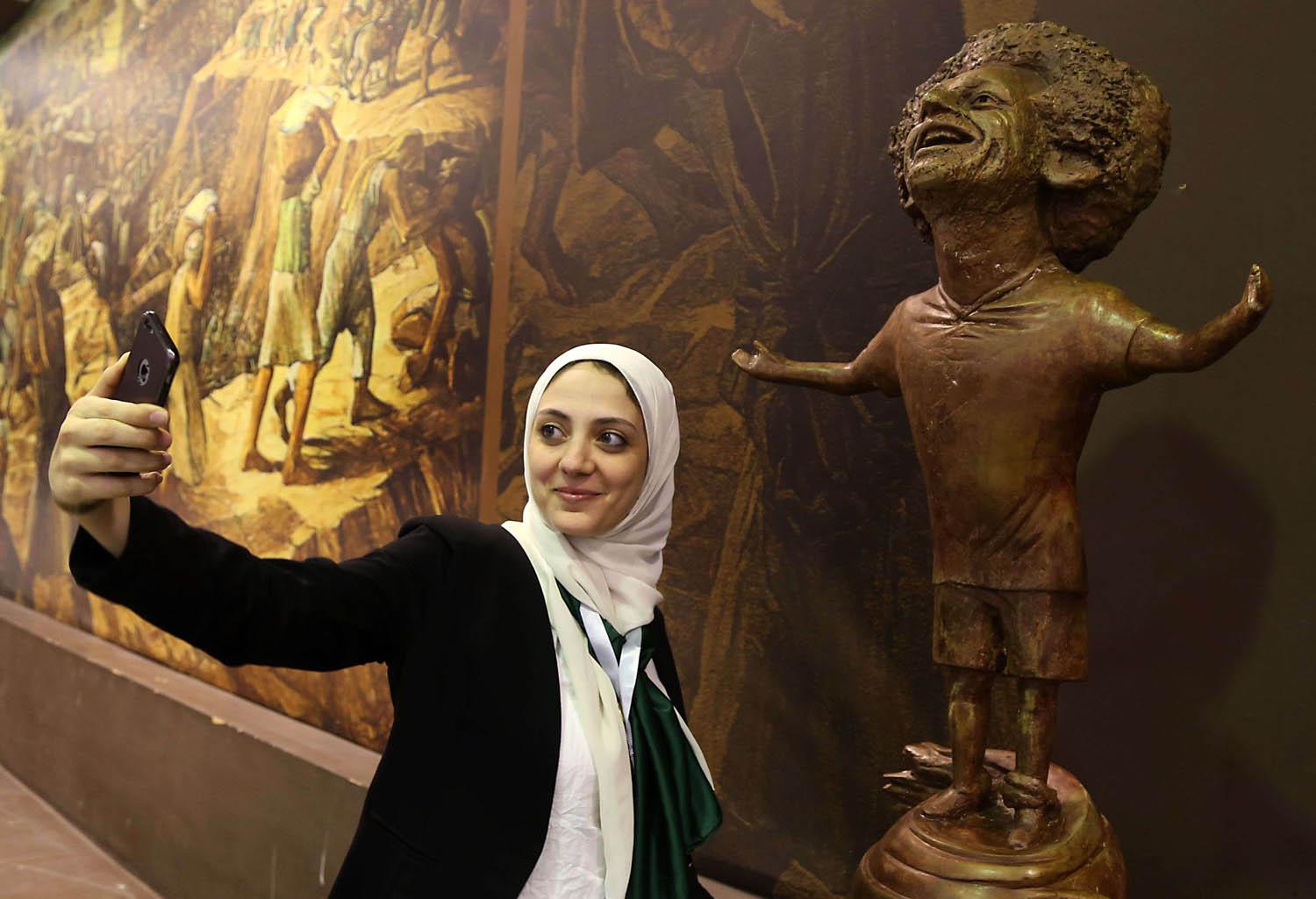 مصرية تأخذ صورة مع تمثال للاعب محمد صلاح في مندى للشباب في شرم الشيخ بمصر