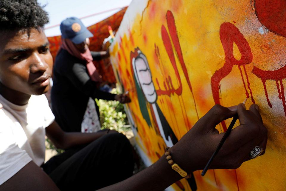 سوداني يرسم على حائط في ساحة الاعتصام