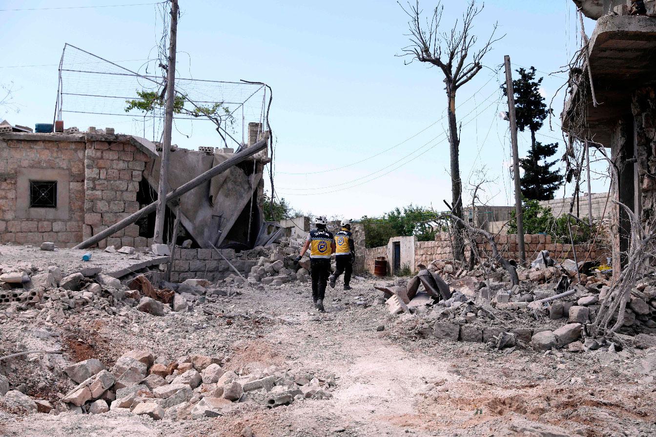 Members of the Syrian Civil Defence, also known as the White Helmets, walk amidst the debris of homes following bombardment by regime forces on the village of Ibdita on May 4, 2019