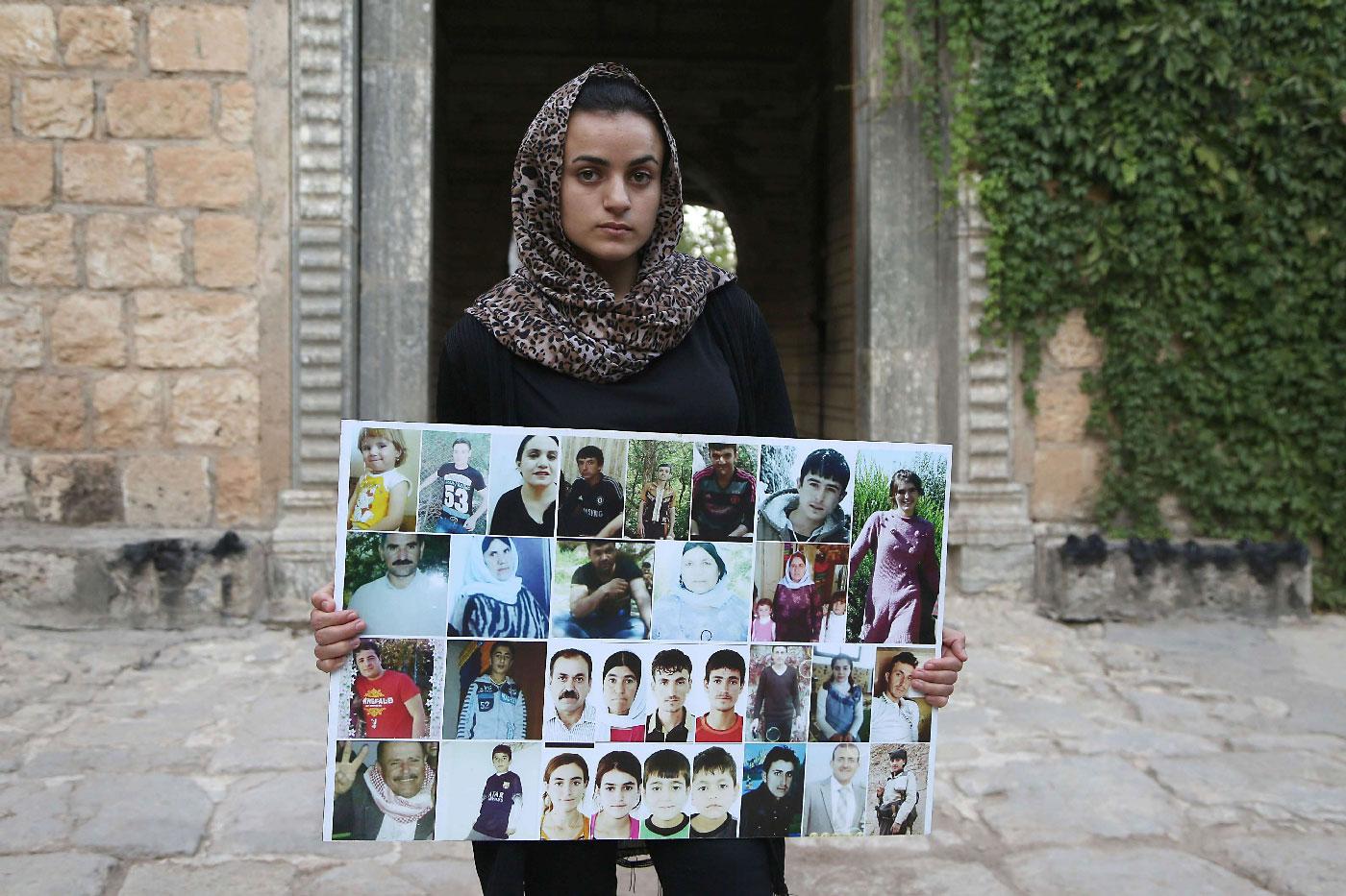 Yazidi woman Ashwaq Haji, allegedly used by the Islamic State group (IS) as a sex slave, holds portraits of jihadists' victims from her village of Kocho near Sinjar