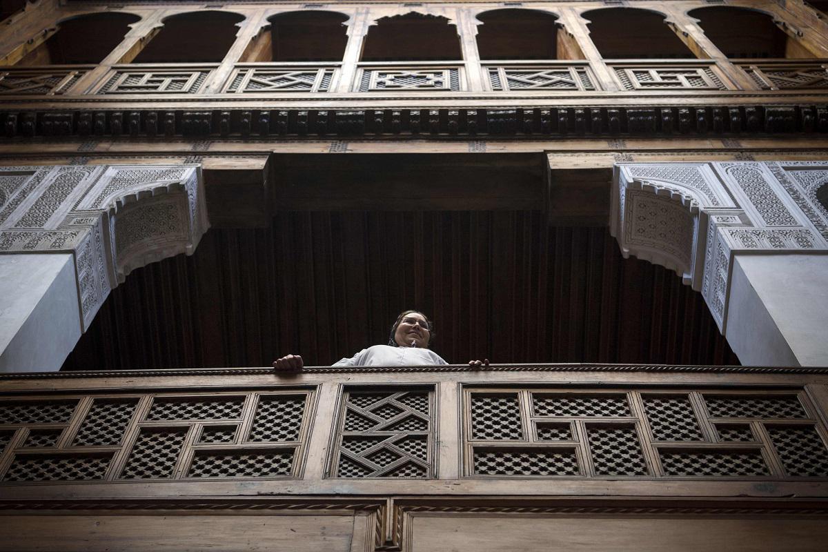 امرأة مغربية تقف على شرفة مبنى تراثي في مدينة فاس القديمة