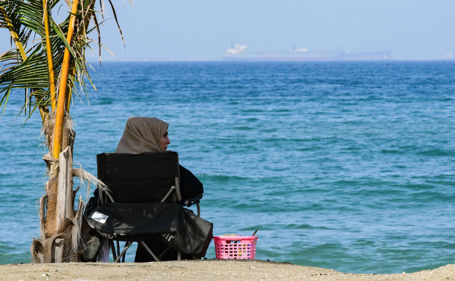 سيدة تجلس على الساحل المطل على خليج عمان في الفجيرة