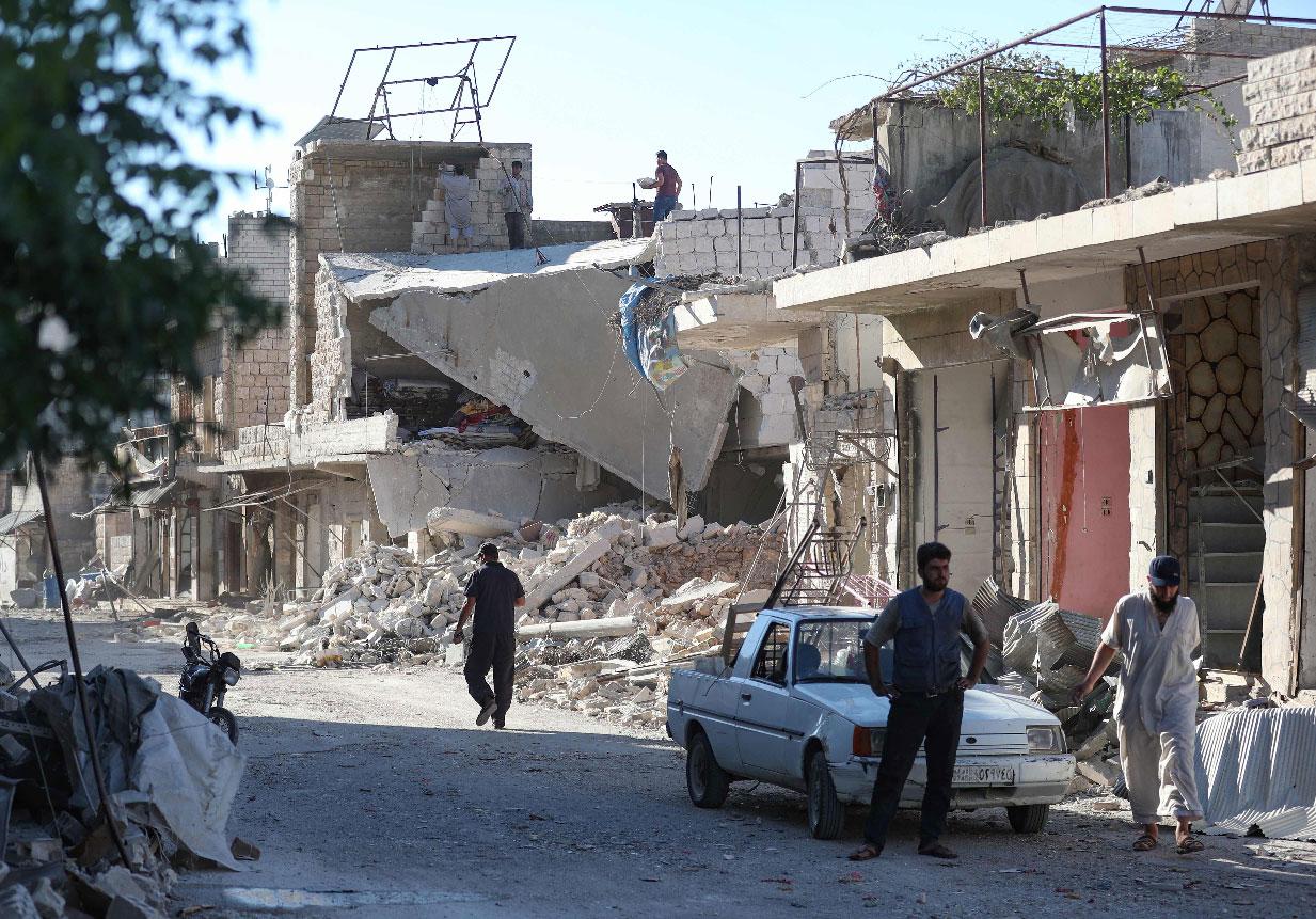 Residents of the village of Kafr Nabl check the damage caused by a pro-regime air strike